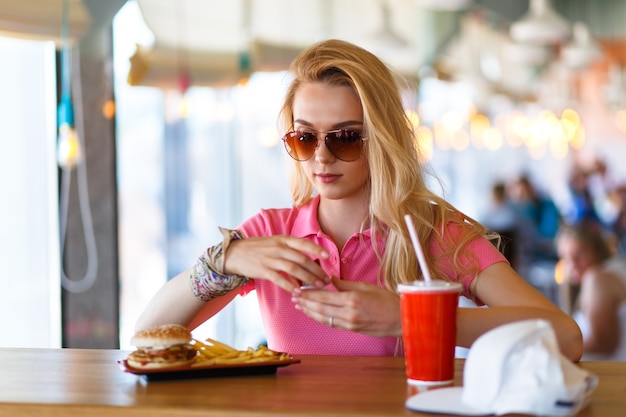 Giovane bella donna che riposa al bar e mangia