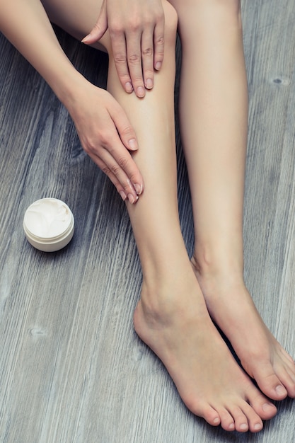 Giovane bella donna che si applica la crema sulle gambe per evitare irritazioni cutanee skin