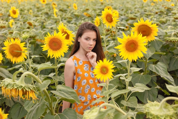 Giovane bella donna che si gode l'estate, la giovinezza e la libertà, tenendo i girasoli contro il cielo blu. Immagine tonica.