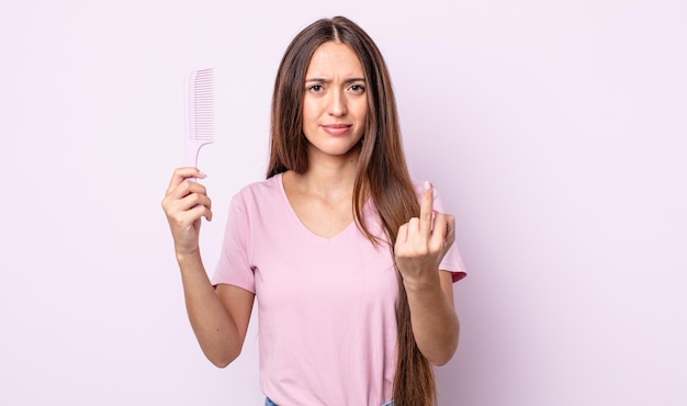 Giovane bella donna che si sente arrabbiata, infastidita, ribelle e aggressiva. concetto di pettine per capelli