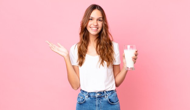 giovane bella donna che si sente felice, sorpresa di realizzare una soluzione o un'idea e con in mano un bicchiere di latte