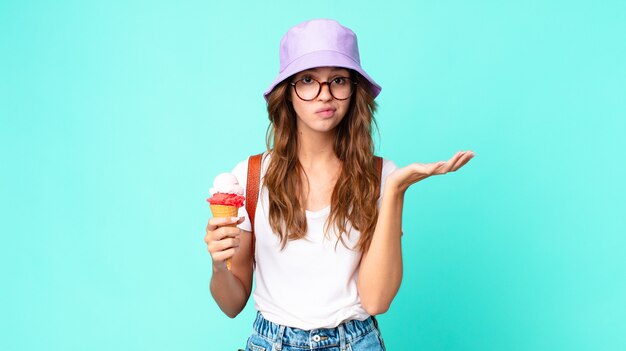 Giovane bella donna che si sente perplessa e confusa e dubita di tenere un gelato. concetto di estate