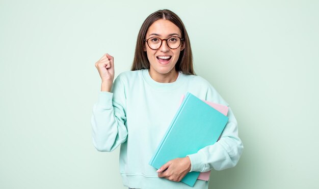 Giovane bella donna che si sente scioccata, ride e celebra il successo. studente universitario