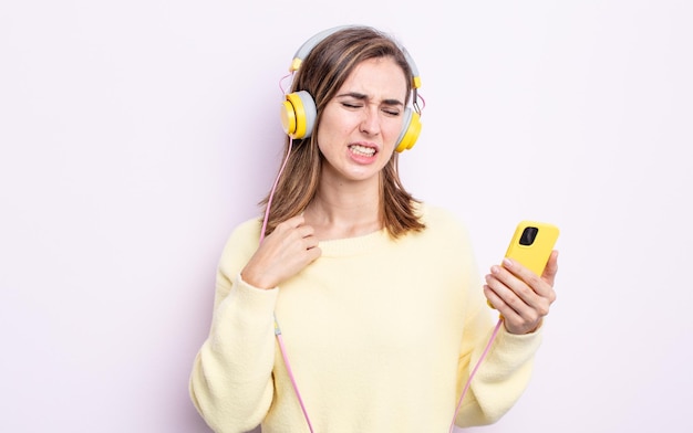 Giovane bella donna che si sente stressata, ansiosa, stanca e frustrata. cuffie e concetto di telefono