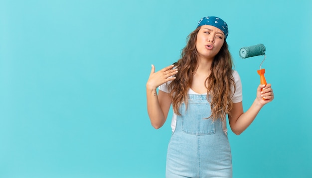 Giovane bella donna che si sente stressata, ansiosa, stanca e frustrata e dipinge un muro