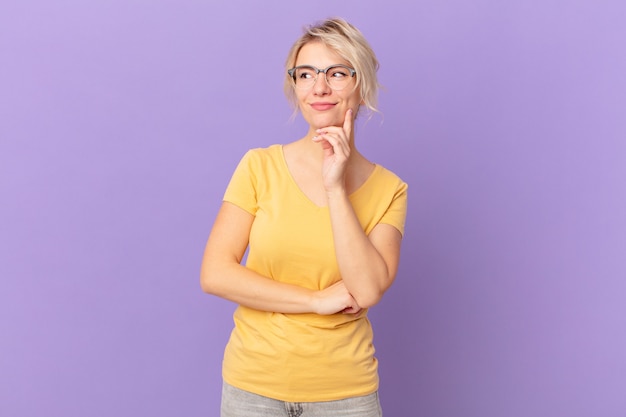 Giovane bella donna che sorride con un'espressione felice e sicura con la mano sul mento