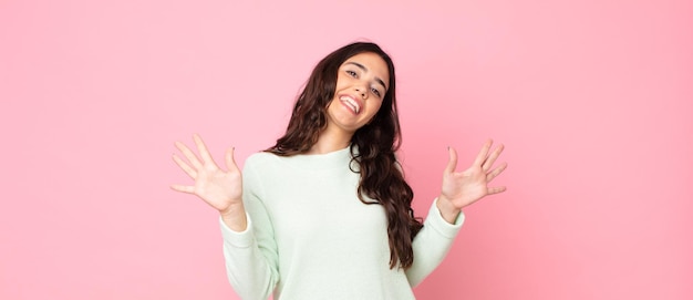 Giovane bella donna che sorride e sembra amichevole, mostrando il numero dieci o decimo con la mano in avanti, conto alla rovescia