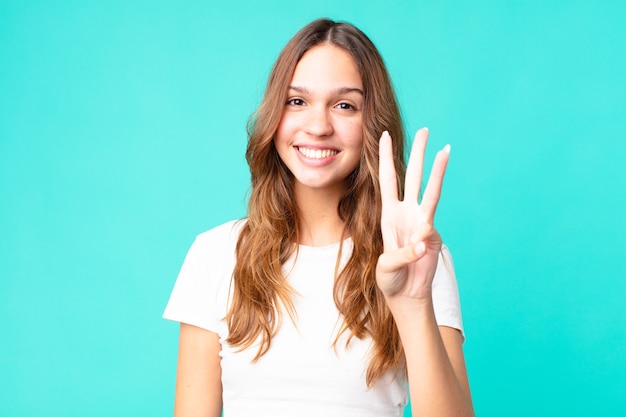 Giovane bella donna che sorride e sembra amichevole, mostrando il numero tre