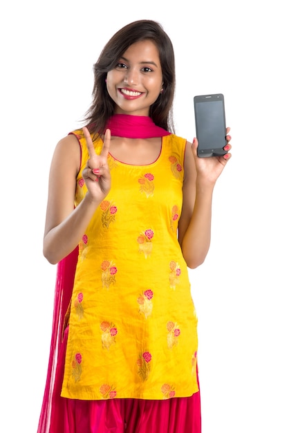Giovane bella donna che tiene e che mostra smartphone schermo vuoto o cellulare o tablet su bianco