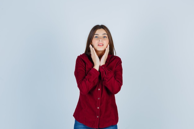 Giovane bella donna che tiene la mano vicino al viso in camicia e sembra sicura