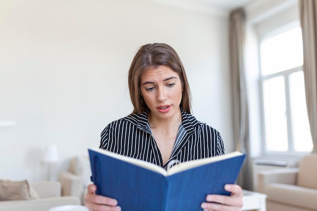 Giovane bella donna che tiene libro Studente universitario che studia l'apprendimento della lingua letteratura per il tempo libero e concetto di persone donna sorridente che legge il libro a casa