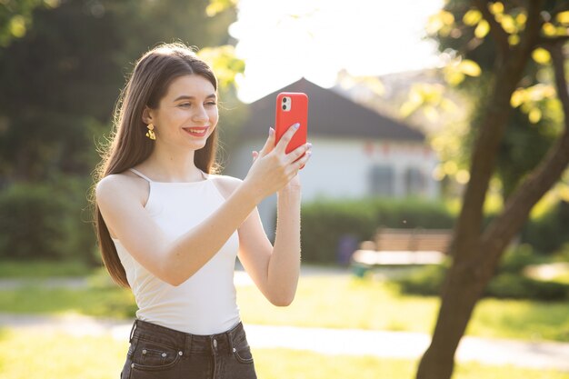 Giovane bella donna che utilizza il telefono nel parco