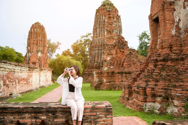 Giovane bella donna che viaggia e che scatta foto al parco storico tailandese