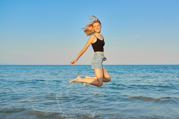 Giovane bella donna che vola sopra il mare femmina felice che salta sopra l'acqua