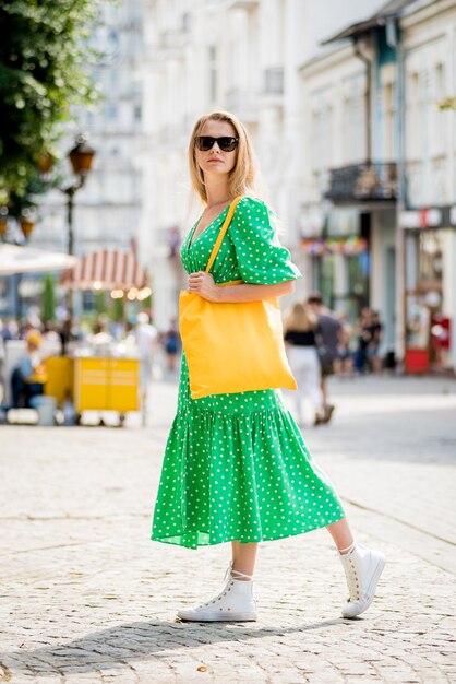 Giovane bella donna con borsa ecologica in lino giallo sullo sfondo della città?