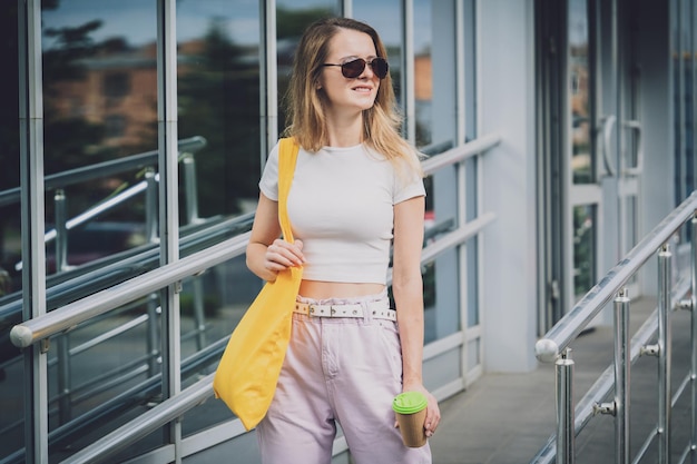 Giovane bella donna con borsa ecologica in lino sullo sfondo della città