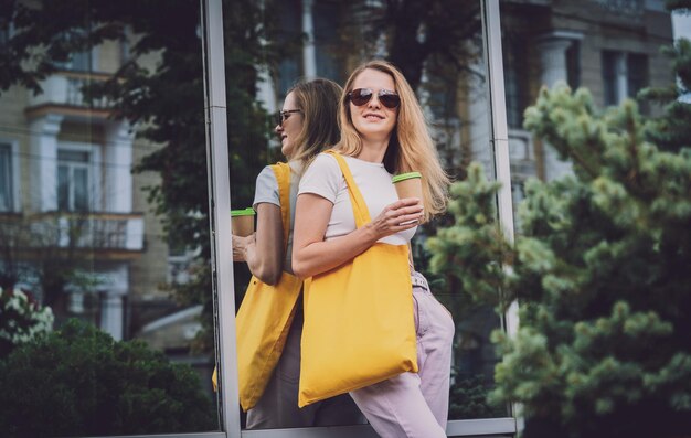 Giovane bella donna con borsa ecologica in lino sullo sfondo della città