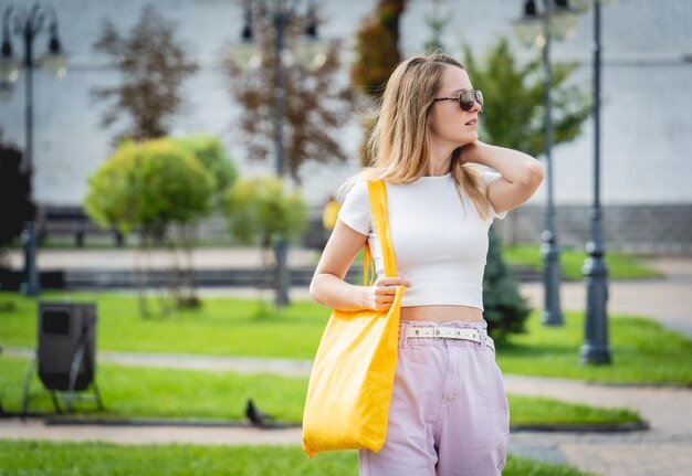 Giovane bella donna con borsa ecologica in lino sullo sfondo della città