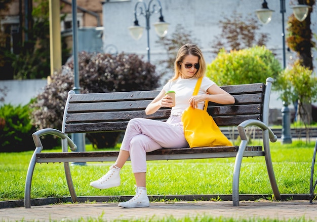 Giovane bella donna con borsa ecologica in lino sullo sfondo della città