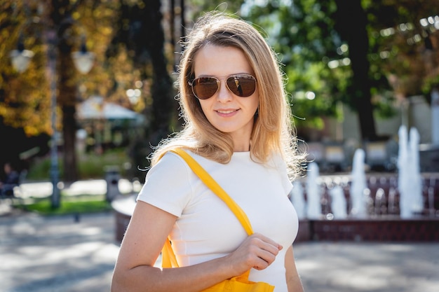 Giovane bella donna con borsa ecologica in lino sullo sfondo della città