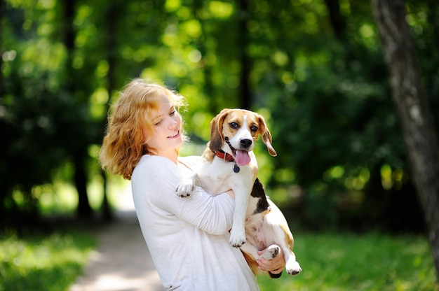 Giovane bella donna con cane Beagle nel parco estivo. Amorevole proprietario femminile con il suo animale domestico domestico