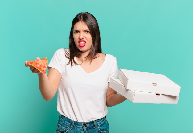 Giovane bella donna con espressione arrabbiata e con in mano una pizza