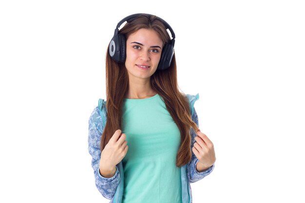 Giovane bella donna con i capelli lunghi in camicia blu che ascolta la musica in cuffie nere