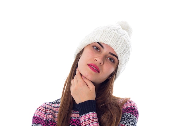 Giovane bella donna con i capelli lunghi in cappello bianco e maglione viola su sfondo bianco in studio