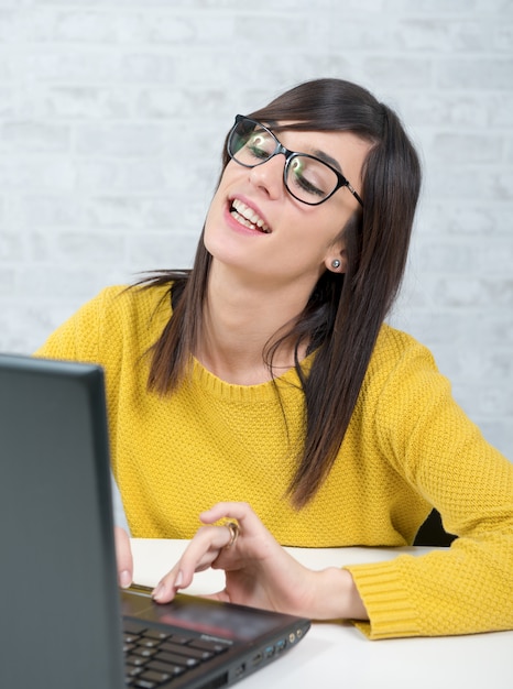 Giovane bella donna con il computer portatile all'ufficio