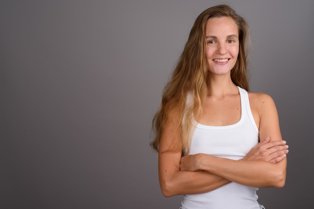 Giovane bella donna con lunghi capelli biondi su sfondo grigio