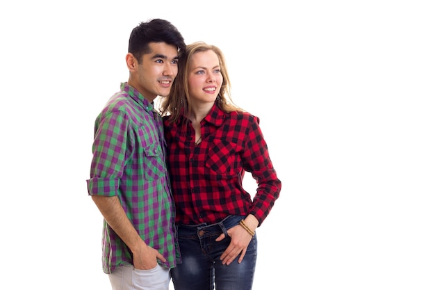 Giovane bella donna con lunghi capelli castani e giovane bell'uomo con i capelli scuri in camicie a quadri e jeans su sfondo bianco in studio