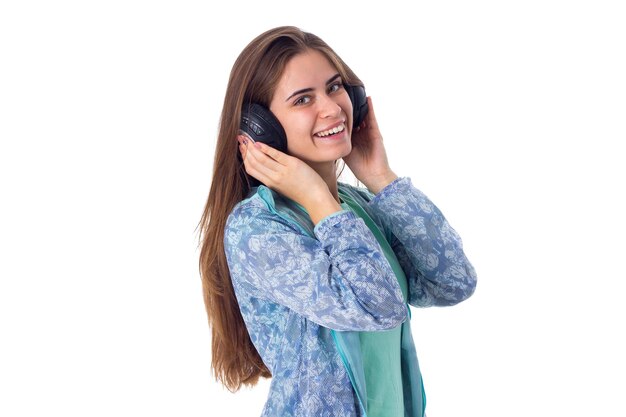 Giovane bella donna con lunghi capelli castani in camicia blu in cuffie nere su sfondo bianco in studio