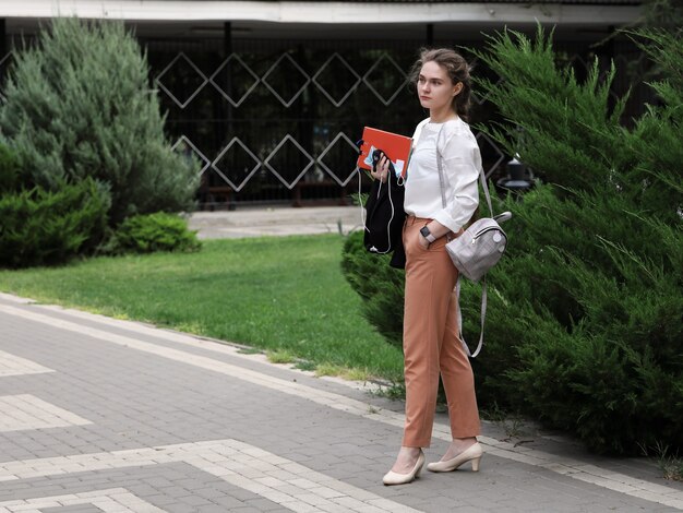 giovane bella donna con materiali didattici nelle sue mani si trova nel parco