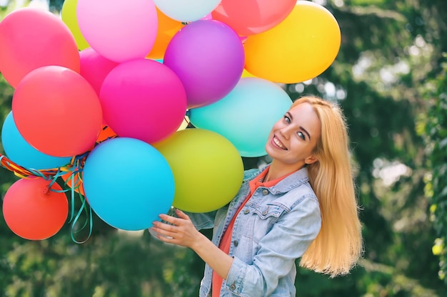 Giovane bella donna con palloncini all'aperto