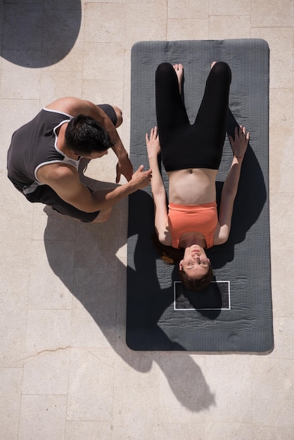 giovane bella donna con personal trainer che fa esercizi di yoga mattutini davanti alla sua lussuosa villa di casa vista dall'alto