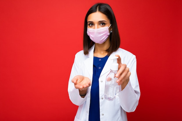 Giovane bella donna con un camice bianco da dottore e una maschera medica sul viso