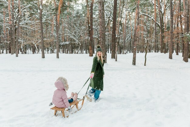 Giovane bella donna con una bambina che si diverte fuori nel parco invernale