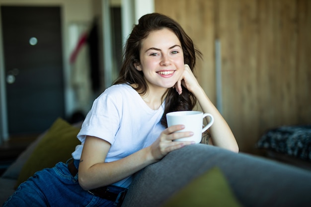 Giovane bella donna con una tazza sul divano di casa