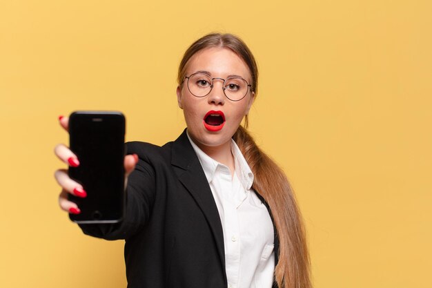 Giovane bella donna. concetto di smartphone con espressione scioccata o sorpresa