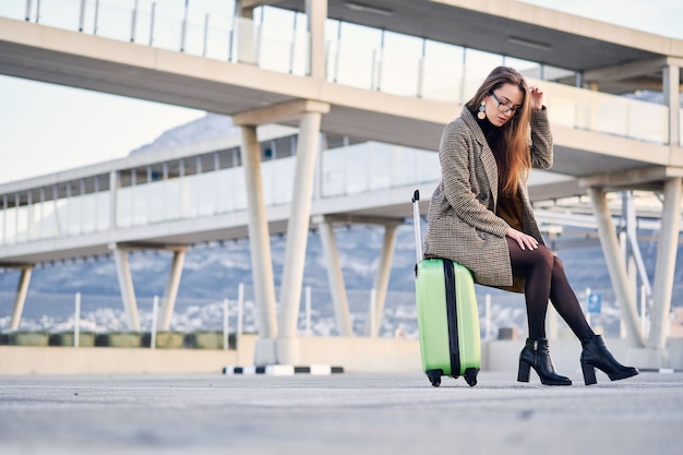 Giovane bella donna d'affari all'aeroporto internazionale con la valigia