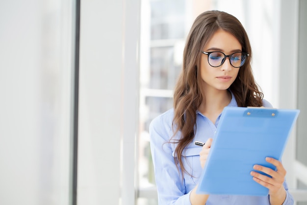 Giovane bella donna d'affari con appunti in ufficio.