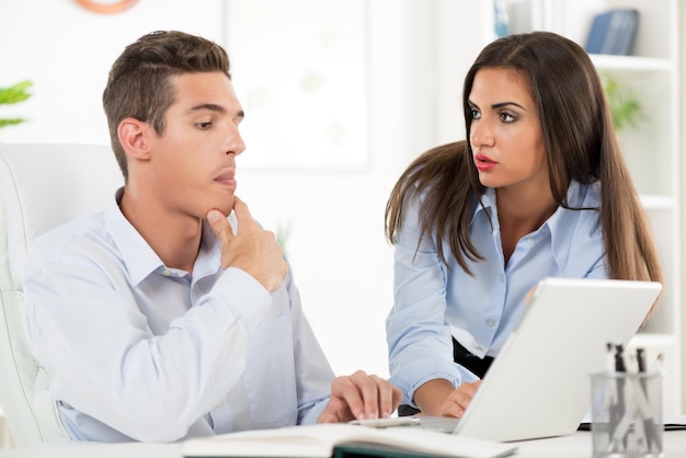 Giovane bella donna d'affari e uomo d'affari che lavora al computer portatile in ufficio.