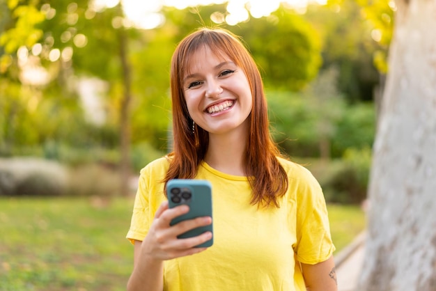 Giovane bella donna dai capelli rossi all'aperto usando il cellulare