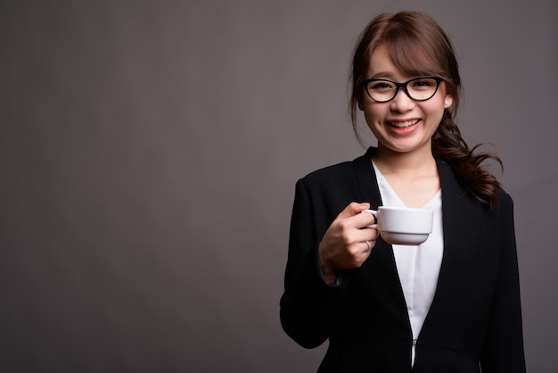 Giovane bella donna di affari asiatica che tiene tazza di caffè
