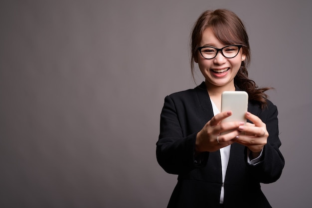 Giovane bella donna di affari asiatica utilizzando il telefono cellulare