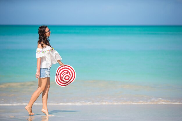 Giovane bella donna divertendosi sulla spiaggia tropicale.