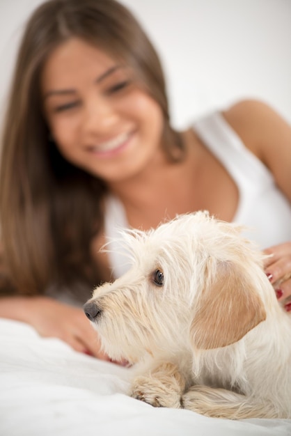 Giovane bella donna e il suo cane che riposano a letto