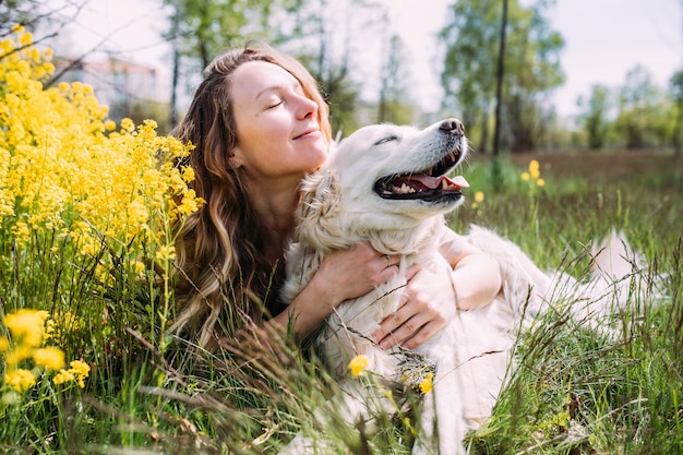 Giovane bella donna e il suo cane golden retriever che si divertono in estate