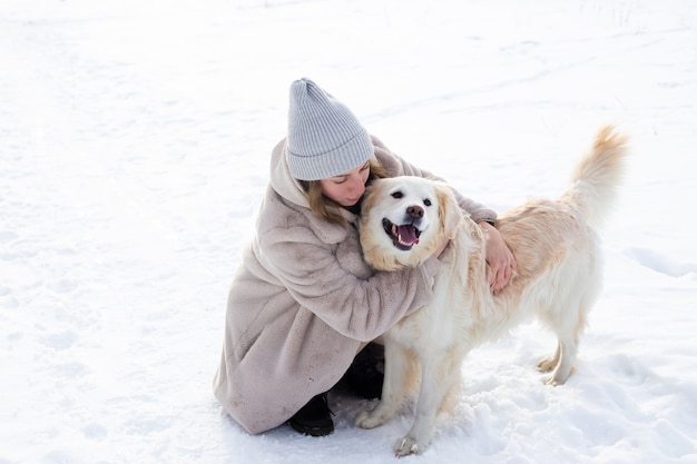 Giovane bella donna e il suo cane golden retriever che si divertono in inverno