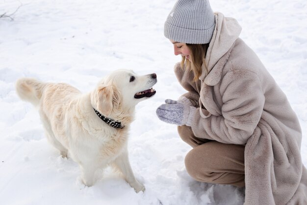 Giovane bella donna e il suo cane golden retriever che si divertono in inverno